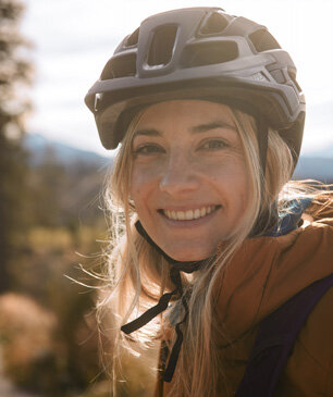 Eine eBikerin mit Helm lächelt.
