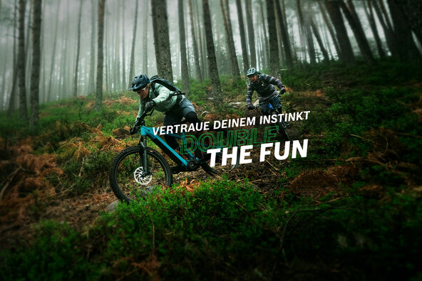 Zwei eBiker im Sportdress fahren mit ihren eMountainbikes einen steilen Trail im Wald hinunter