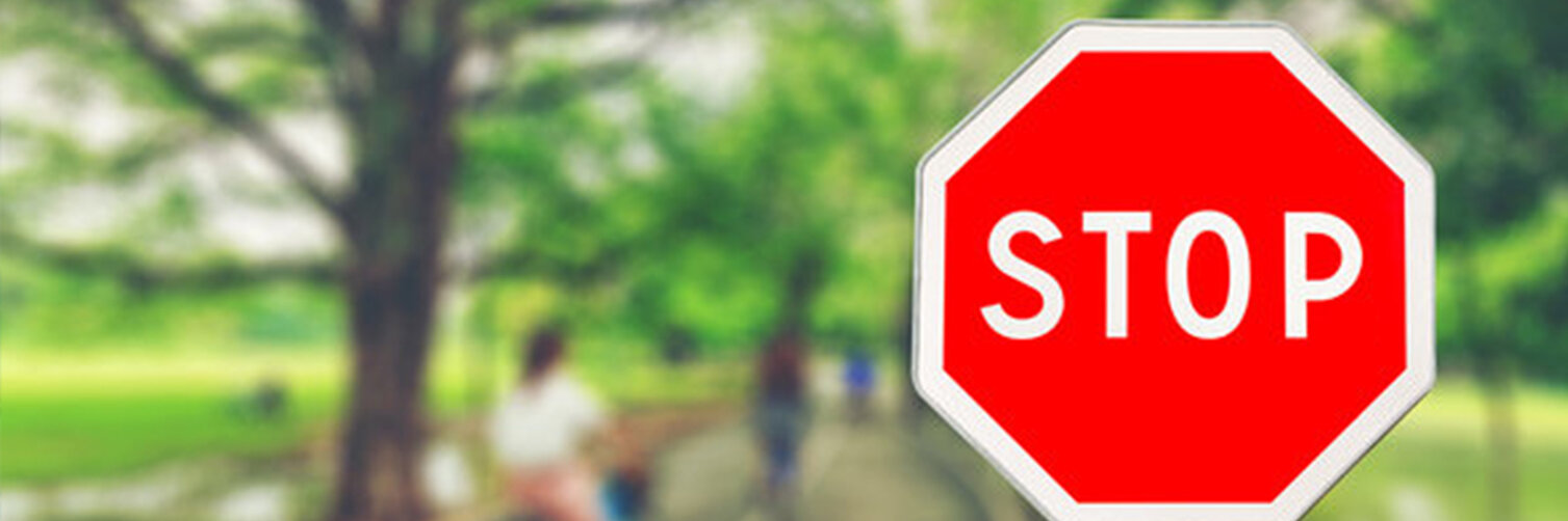 Ein Stoppschild vor einem unscharfen Hintergrund, der eBiker auf einem Waldweg zeigt