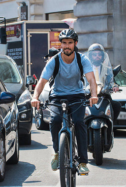 Ein Mann mit eBike im Stadtverkehr, hinter ihm fährt ein Motorroller